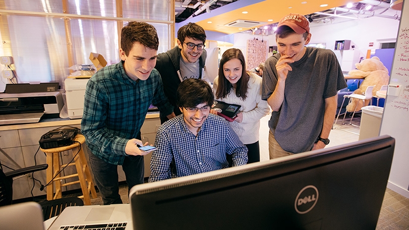 a group of students gathered around a computer