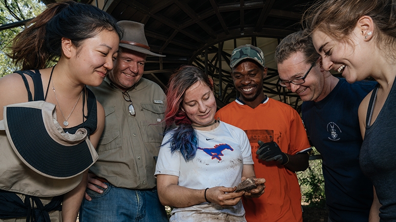 students examining a fossilized bone on an anthropology dig in South Africa